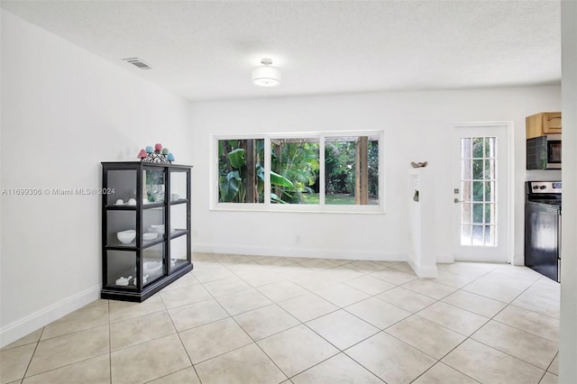 spare room featuring a textured ceiling, a healthy amount of sunlight, and light tile patterned flooring