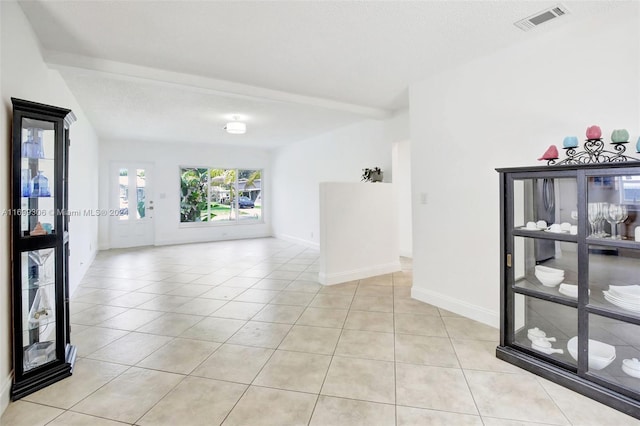 tiled empty room with beam ceiling and a textured ceiling