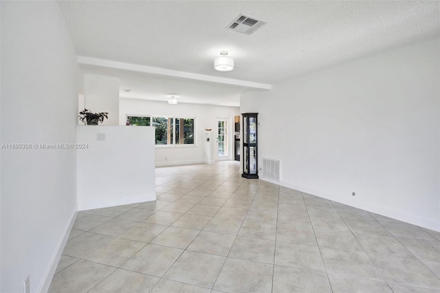 tiled empty room with a textured ceiling