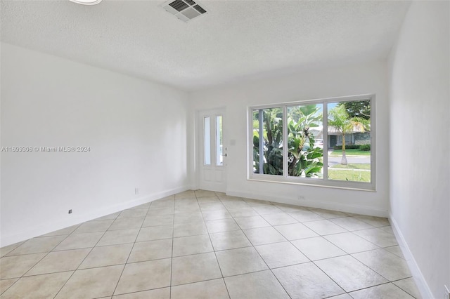 unfurnished room featuring a textured ceiling and light tile patterned flooring