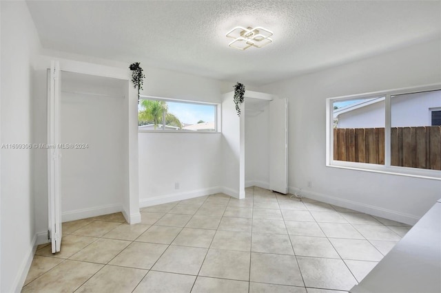 unfurnished bedroom featuring light tile patterned flooring and a textured ceiling