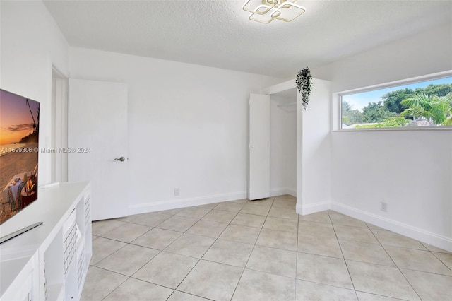 tiled empty room featuring a textured ceiling