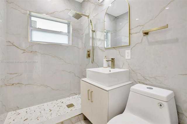 bathroom with a tile shower, vanity, toilet, and tile walls