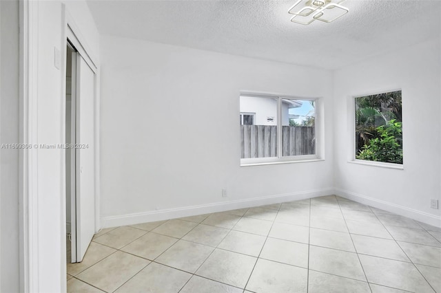 unfurnished room with light tile patterned floors and a textured ceiling