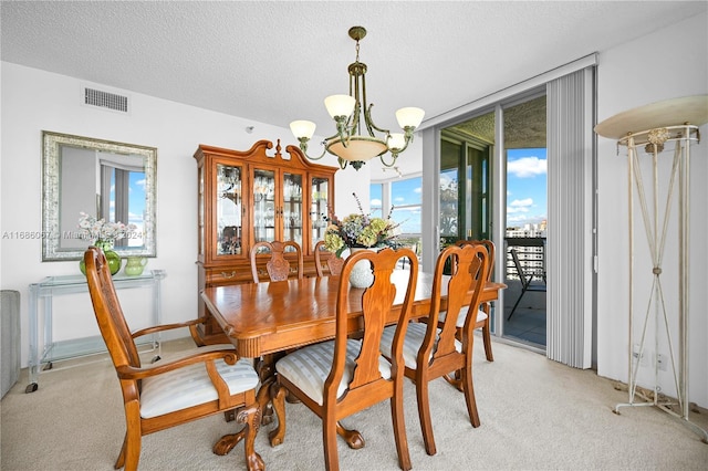 dining space with a textured ceiling, light colored carpet, and a notable chandelier