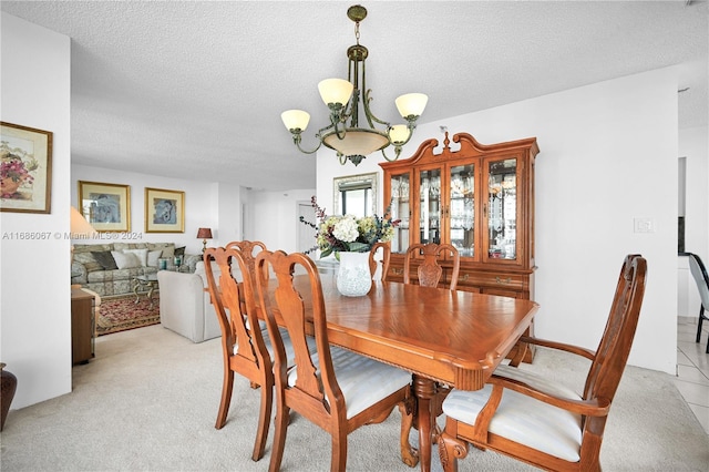 dining room featuring light carpet, a textured ceiling, and a notable chandelier