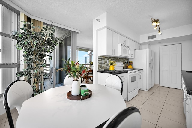 kitchen featuring white cabinetry, backsplash, a textured ceiling, white appliances, and light tile patterned floors