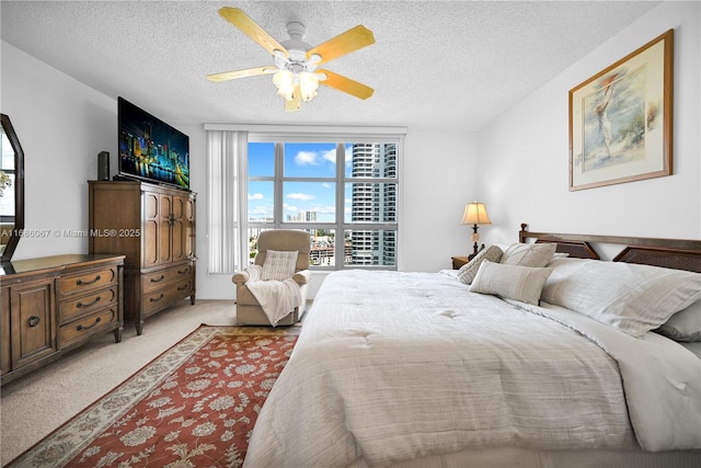 bedroom featuring a ceiling fan, light colored carpet, and a textured ceiling