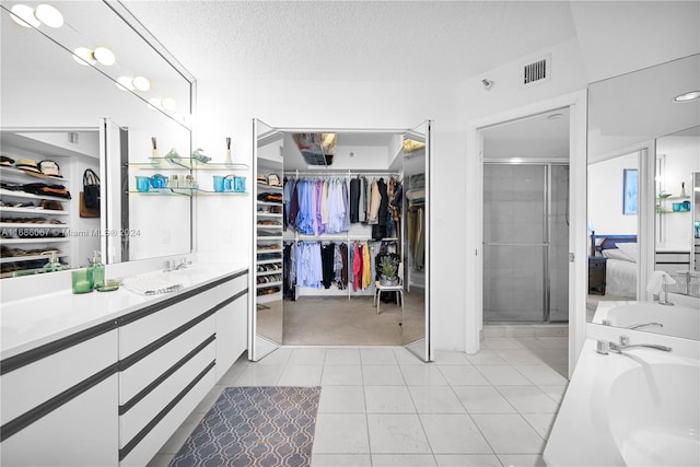 bathroom with tile patterned flooring, vanity, a textured ceiling, and walk in shower