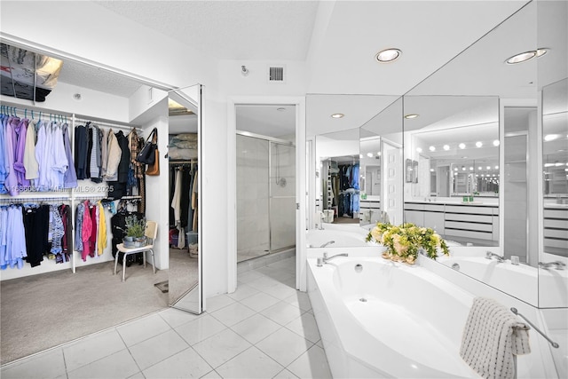 bathroom with a walk in closet, a garden tub, visible vents, a stall shower, and vanity