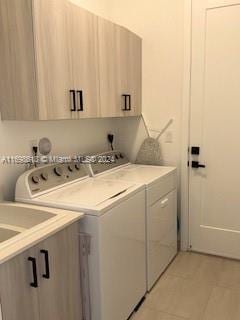 clothes washing area with cabinets, washing machine and dryer, and light tile patterned flooring