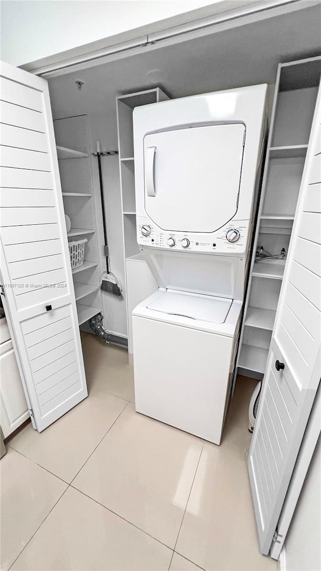 laundry room with light tile patterned flooring and stacked washer and clothes dryer