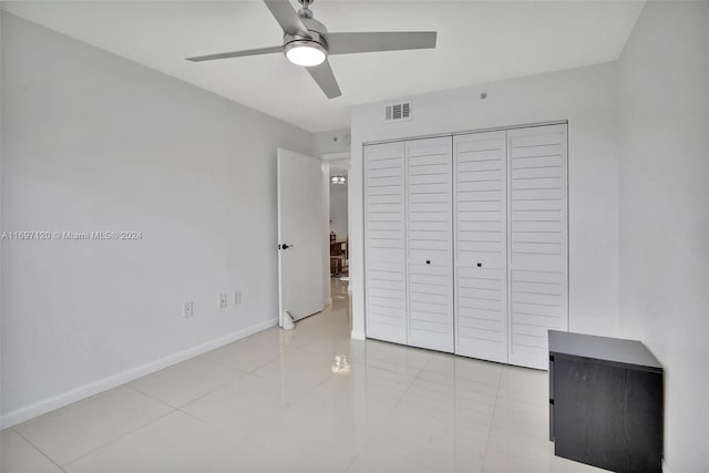 unfurnished bedroom featuring ceiling fan, light tile patterned flooring, and a closet