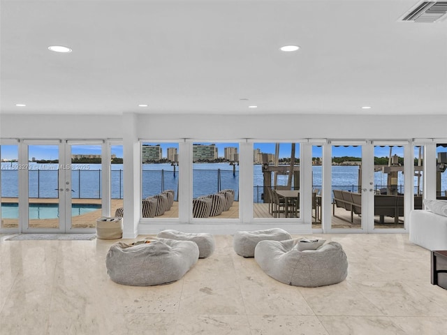 living room featuring a healthy amount of sunlight, a water view, and french doors