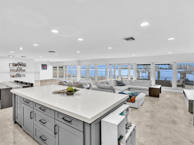 kitchen featuring gray cabinets, a wealth of natural light, a water view, and a kitchen island