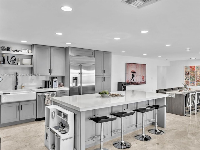 kitchen featuring a kitchen island, sink, stainless steel appliances, and a breakfast bar area