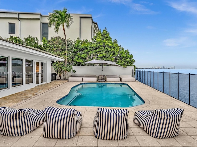 view of pool with a water view and a patio