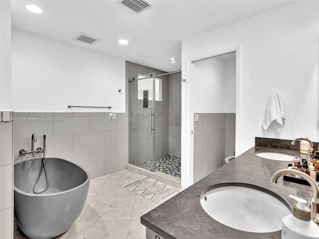 bathroom featuring tile patterned flooring, vanity, tile walls, and independent shower and bath