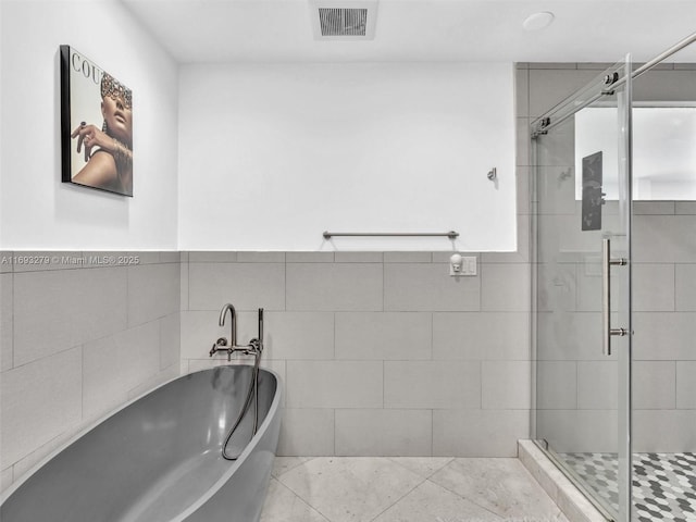 bathroom featuring shower with separate bathtub, tile patterned floors, and tile walls