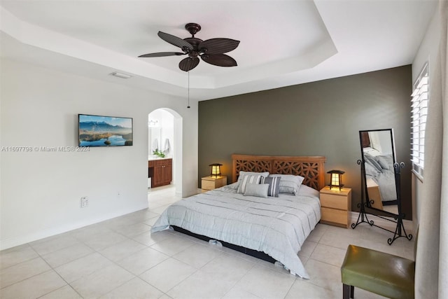 bedroom with light tile patterned floors, a tray ceiling, and ceiling fan