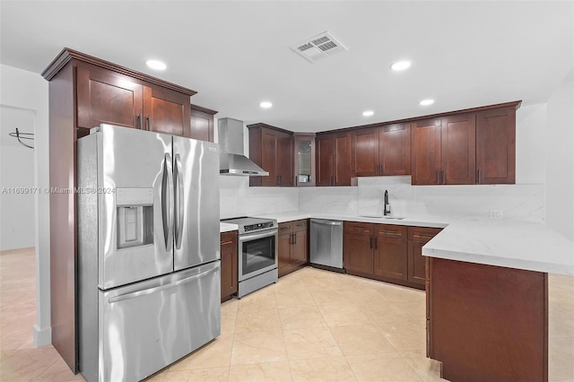 kitchen with kitchen peninsula, sink, stainless steel appliances, and wall chimney range hood