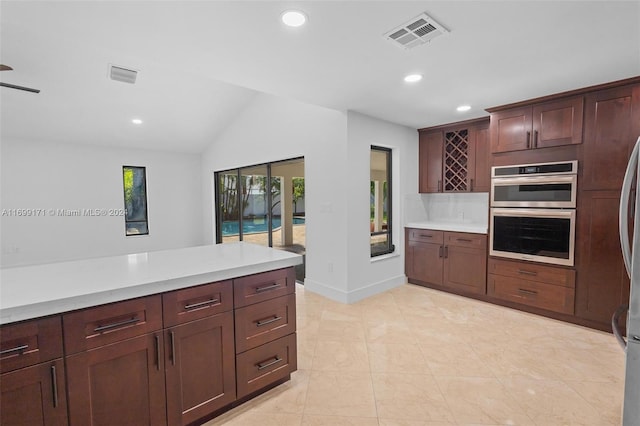 kitchen featuring vaulted ceiling, double oven, and light tile patterned flooring