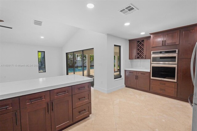 kitchen with kitchen peninsula, decorative backsplash, wall chimney exhaust hood, stainless steel appliances, and sink