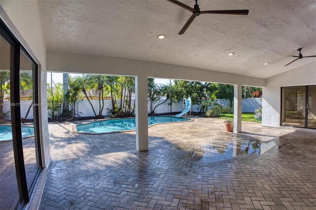 view of swimming pool with ceiling fan, a patio, and a water slide