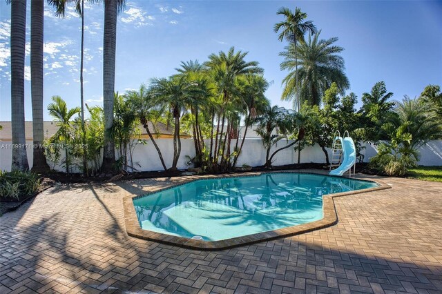 view of pool with a patio area and a water slide