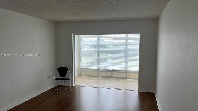 empty room featuring a textured ceiling and dark hardwood / wood-style floors