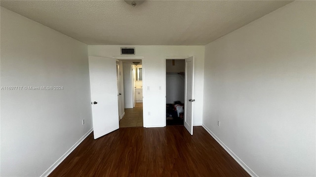 unfurnished bedroom featuring dark hardwood / wood-style flooring, a textured ceiling, and a closet