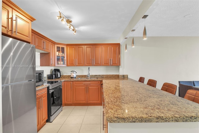 kitchen with sink, appliances with stainless steel finishes, decorative light fixtures, kitchen peninsula, and a breakfast bar area