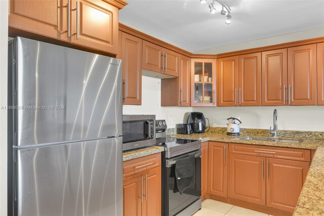 kitchen with sink, rail lighting, stainless steel appliances, light stone counters, and light tile patterned floors