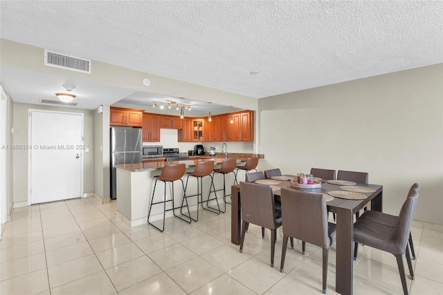 dining room with sink, light tile patterned floors, and a textured ceiling