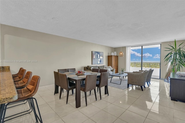 dining area featuring a wall of windows, a textured ceiling, and light tile patterned floors