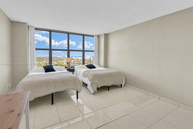 bedroom with light tile patterned floors, expansive windows, and a textured ceiling