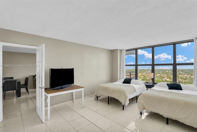 bedroom with light tile patterned floors, a textured ceiling, and multiple windows