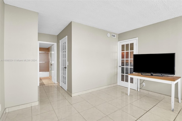 unfurnished living room featuring french doors, a textured ceiling, and light tile patterned flooring