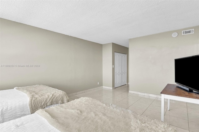 tiled bedroom with a textured ceiling and a closet