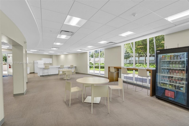 carpeted dining room with wine cooler and a drop ceiling