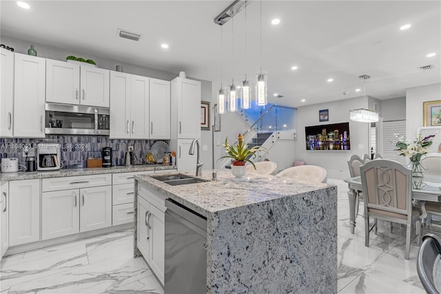 kitchen with hanging light fixtures, sink, an island with sink, and appliances with stainless steel finishes