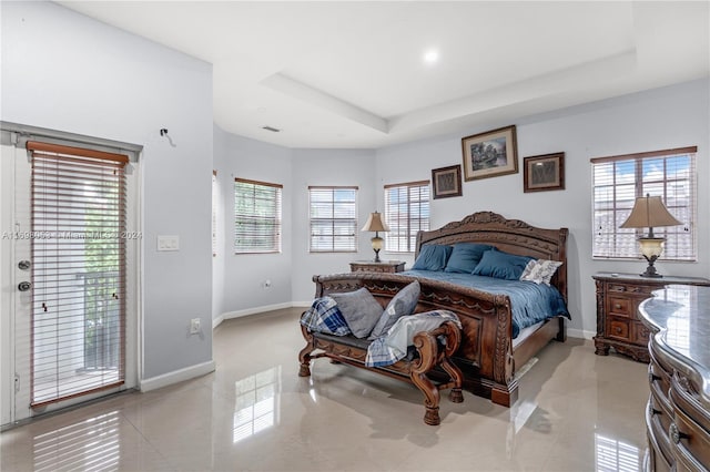 tiled bedroom featuring a raised ceiling, access to exterior, and multiple windows