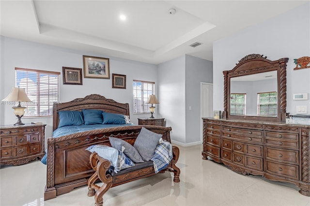 bedroom with a raised ceiling and multiple windows