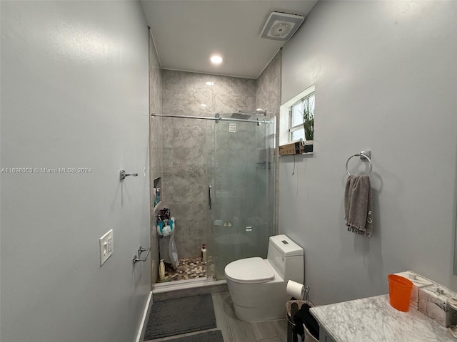 bathroom with vanity, toilet, and a shower with door