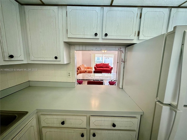 kitchen featuring decorative backsplash, white fridge, and sink