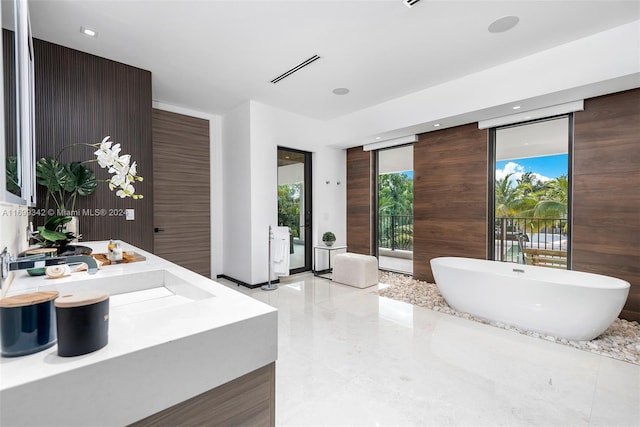 bathroom with vanity, a bathtub, and a wall of windows