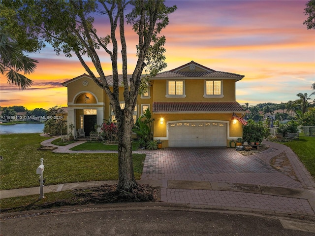 mediterranean / spanish-style house with a lawn, a water view, and a garage