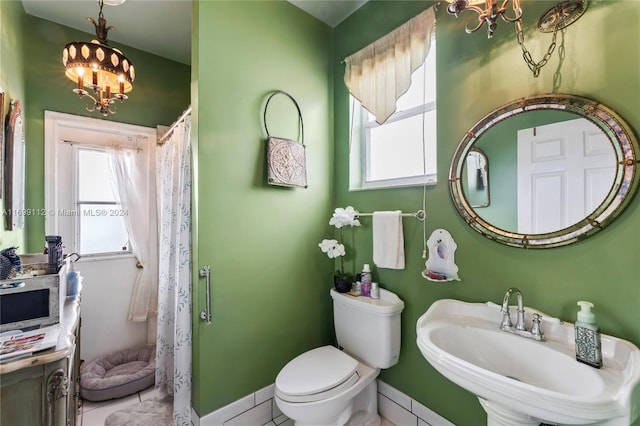 bathroom featuring tile patterned flooring, toilet, sink, and a chandelier