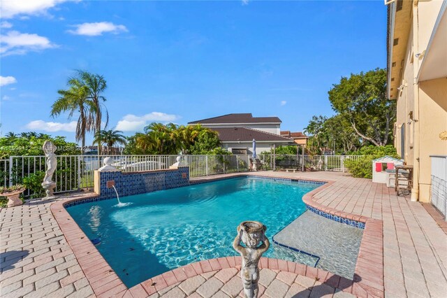 view of pool with a patio area, pool water feature, and an in ground hot tub