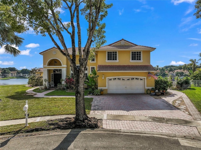 mediterranean / spanish-style home featuring a water view, a garage, and a front lawn